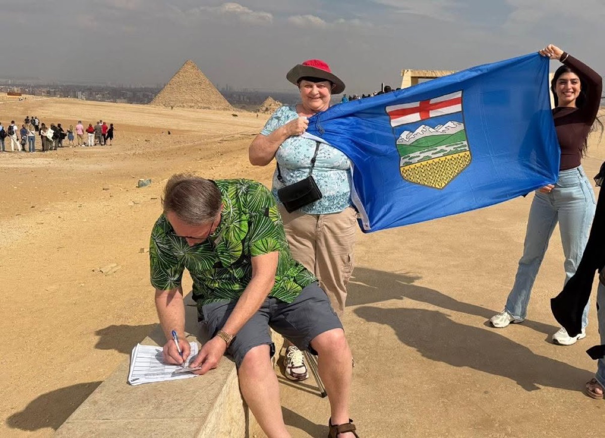 An Albertan signing the petition at the pyramids of Giza with an Alberta flag